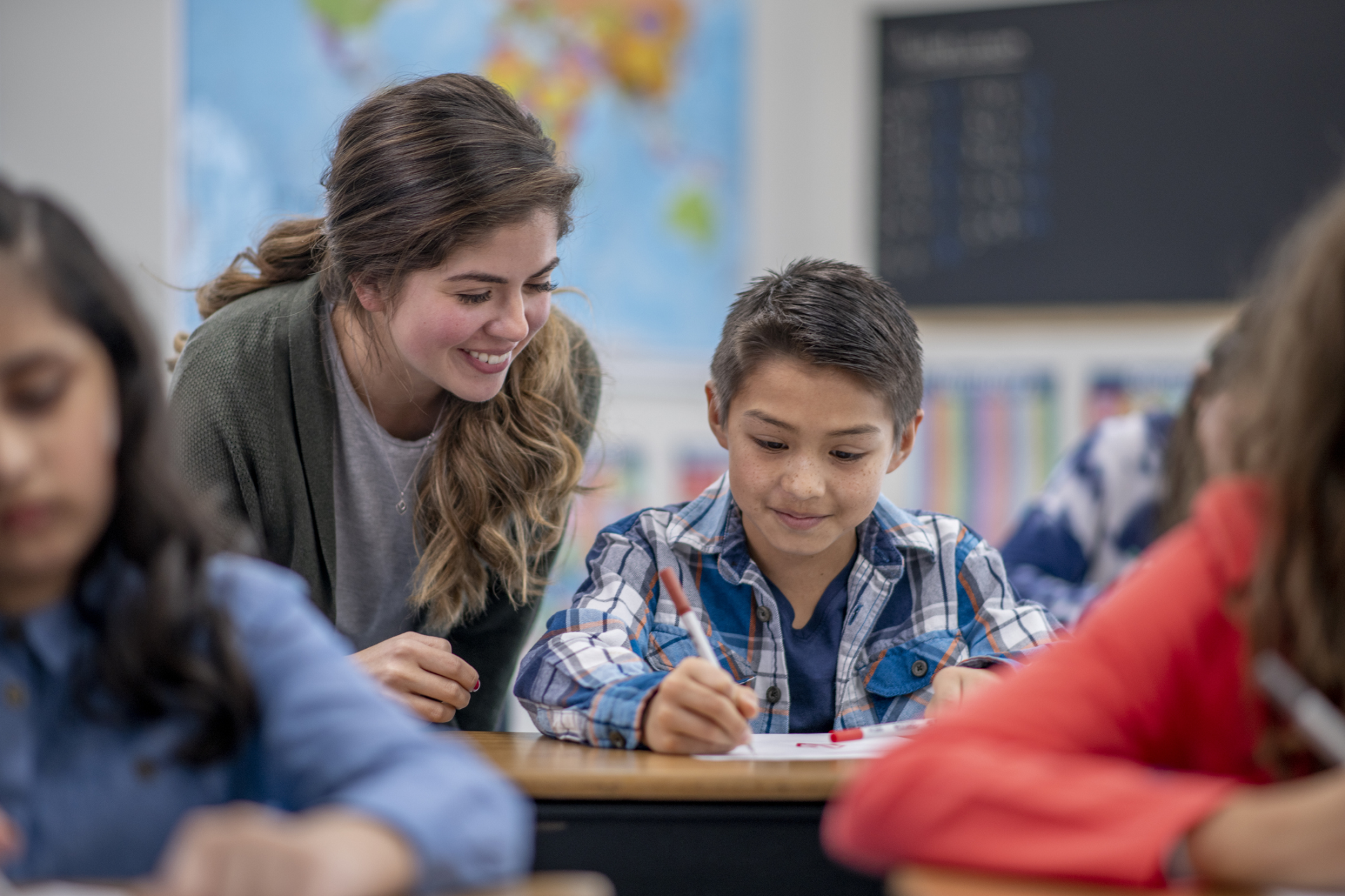 Teacher helping student at their desk.