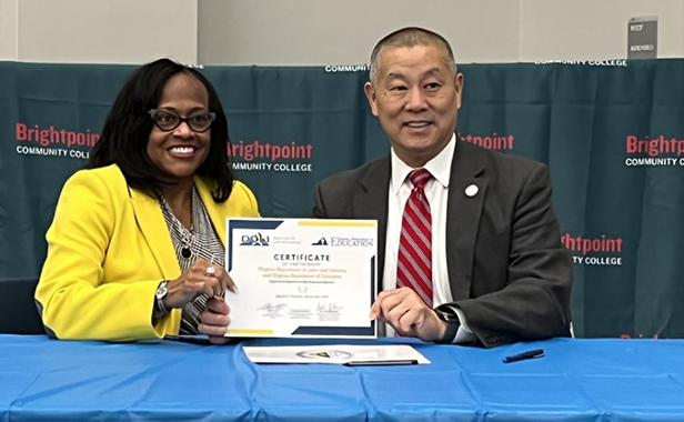 A picture of representatives from VDOE and DOLI holding a signed certificate together.