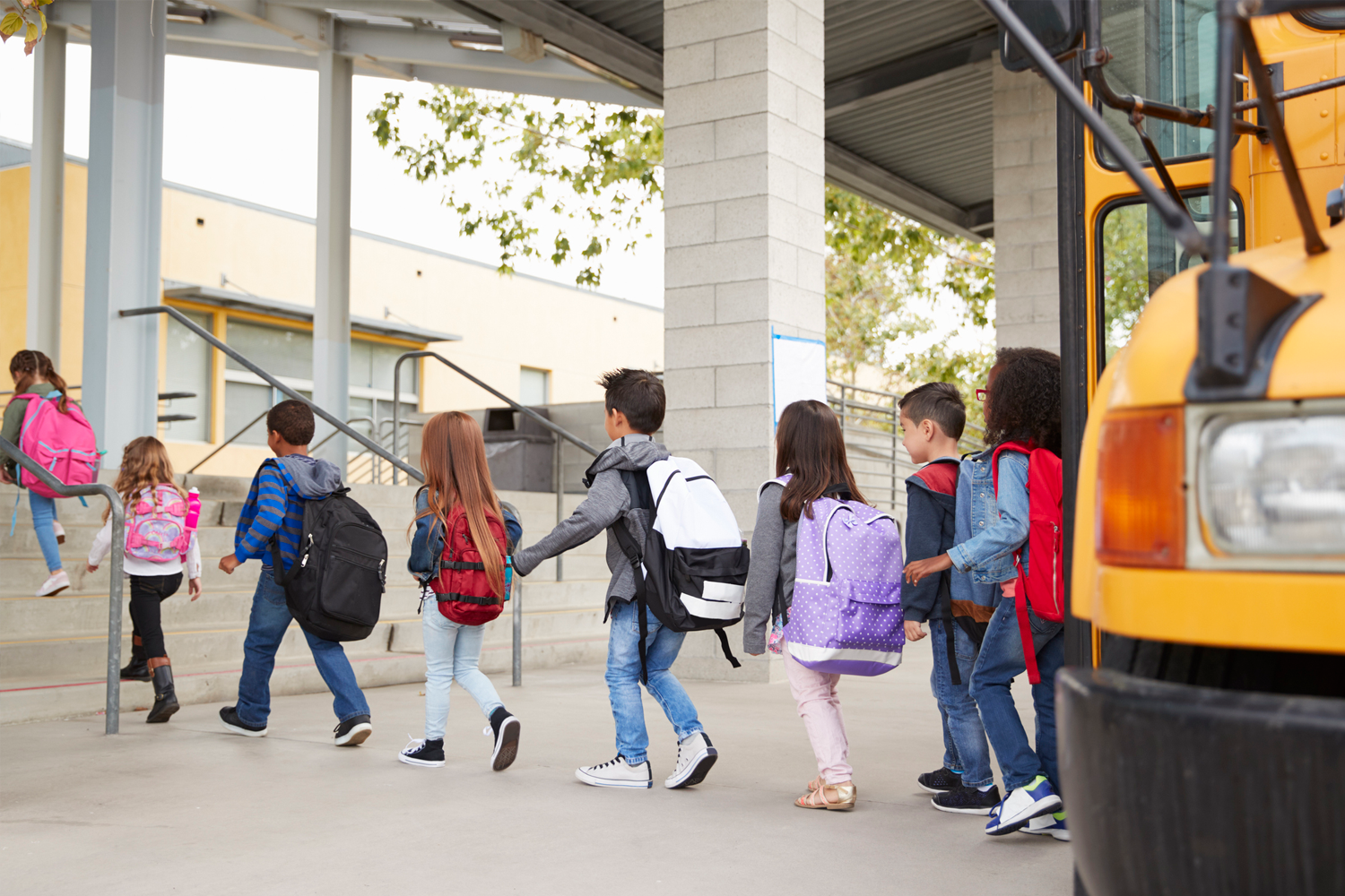 Students departing their school bus and walking into school.