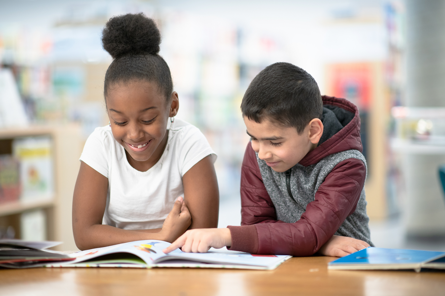 Two elementary students reading a book together.