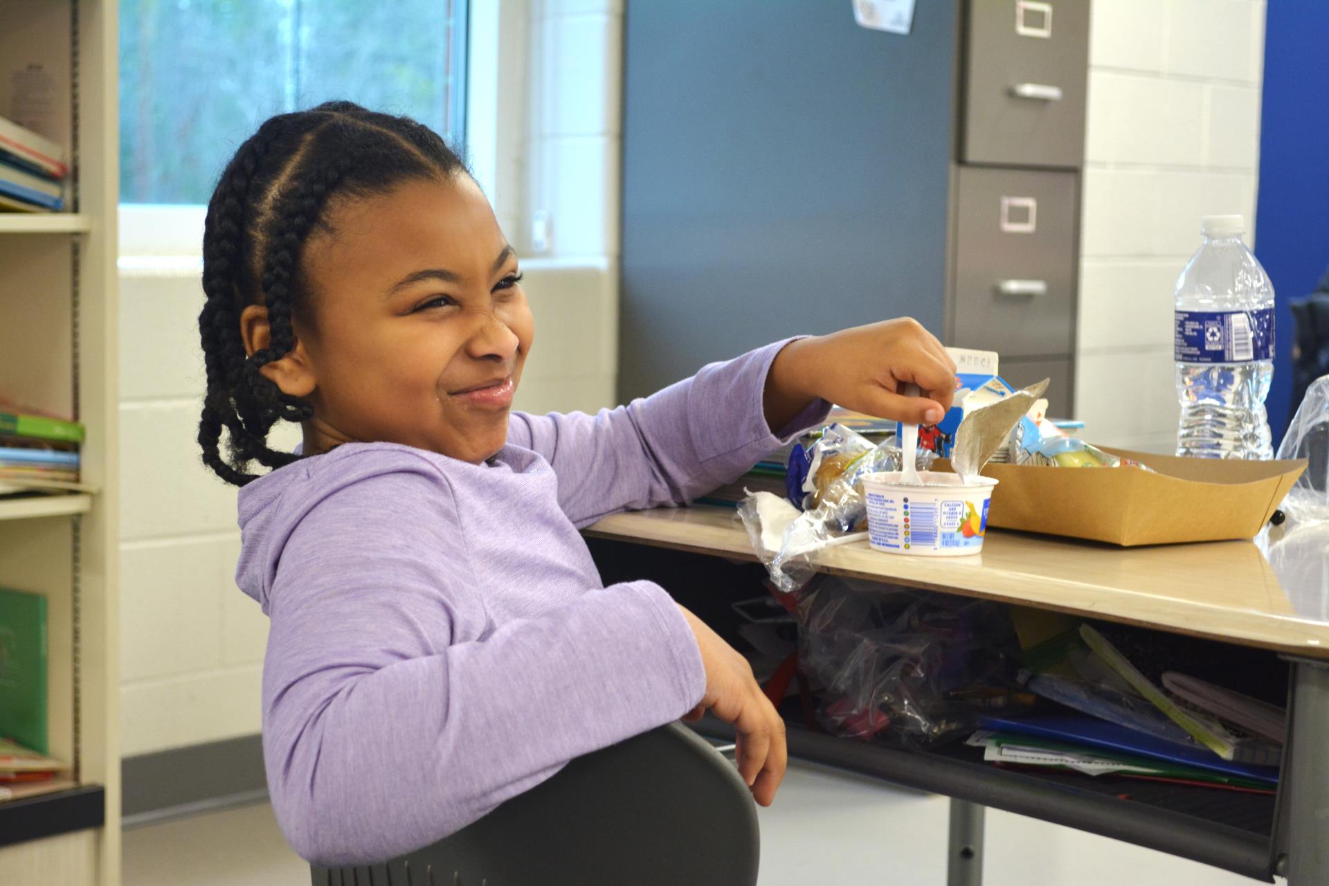 Student eating yogurt in the classroom.