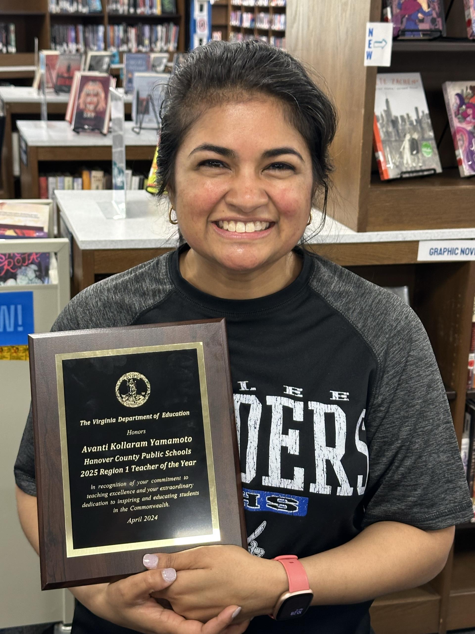 Avanti Yamamoto smiling, holding a Regional Teacher of the Year plaque