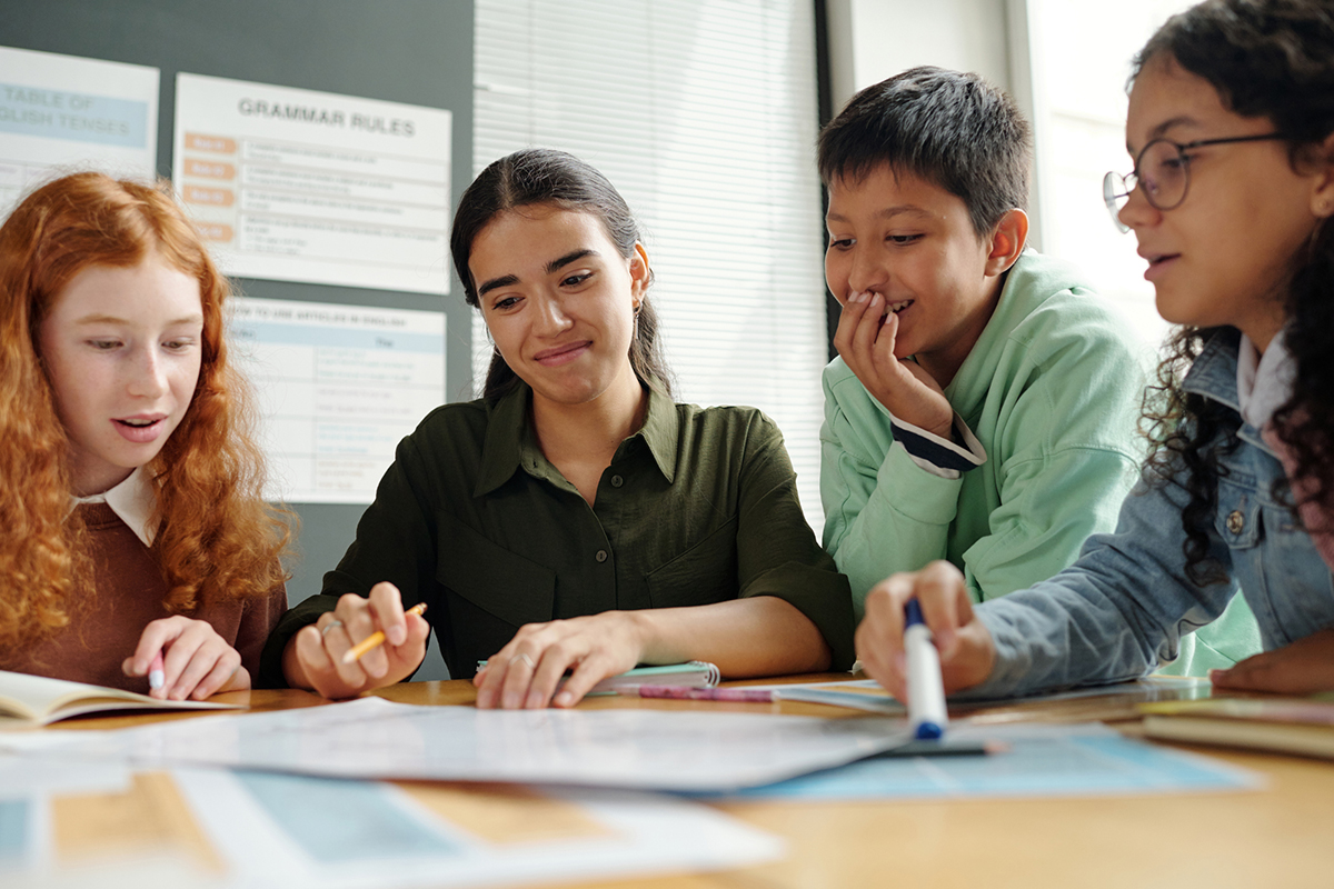 Teacher works with three students at a table.