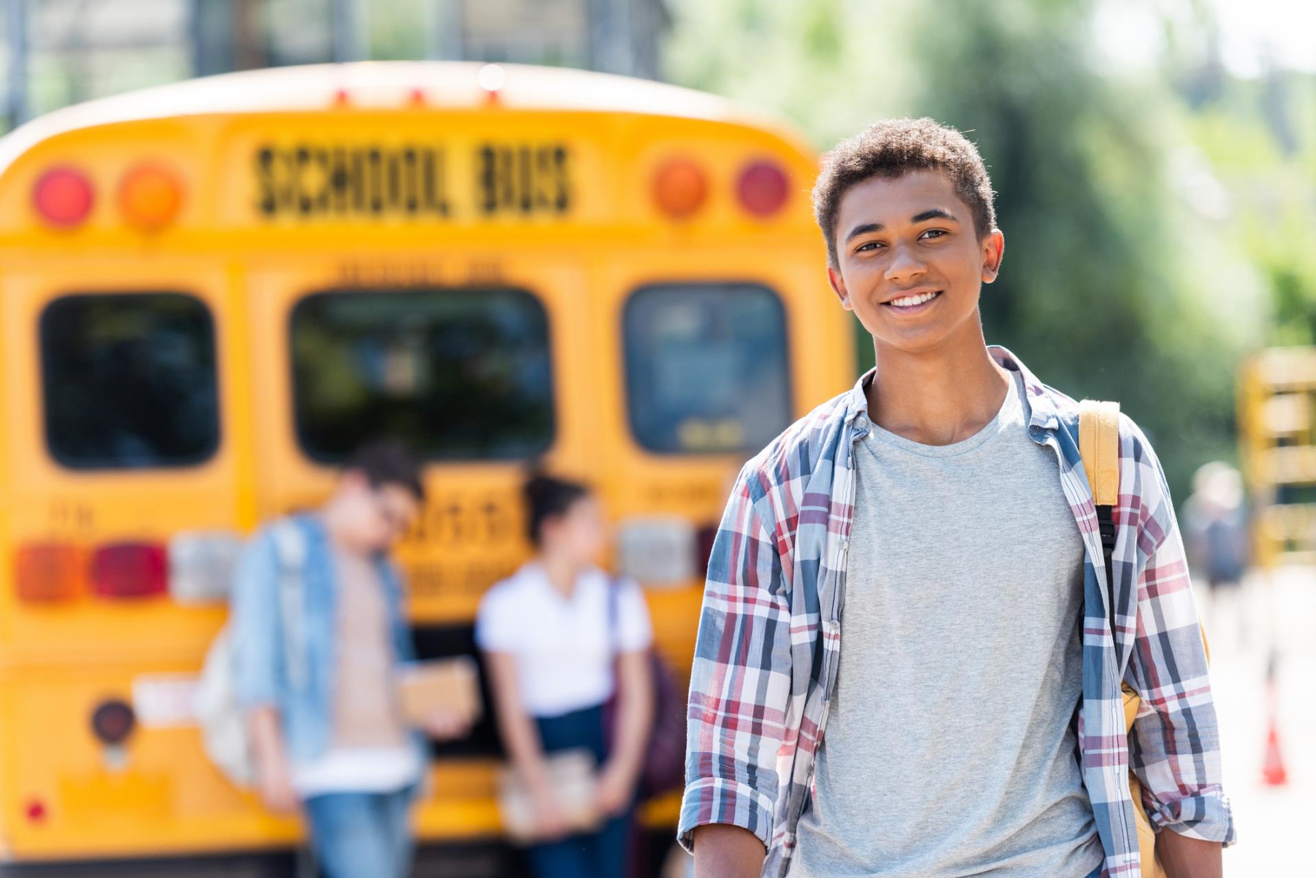 Smiling high school student in front of bus